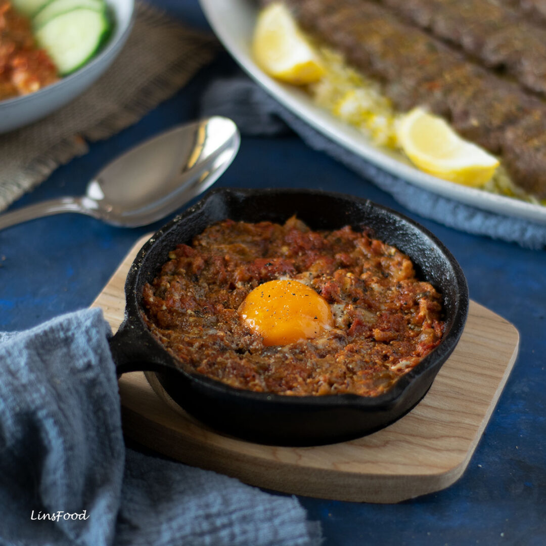 mirza ghasemi, persian smoky aubergine and tomato dip top with runny yolk in a small cast iron pan