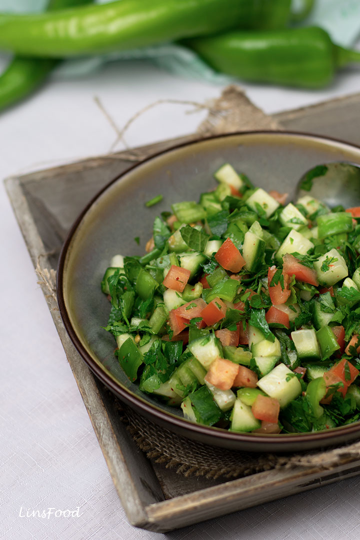 Çoban Salatası (turkish shepherd salad) of chopped up cucumbers and tomatoes in a brown bowl on a wooden tray