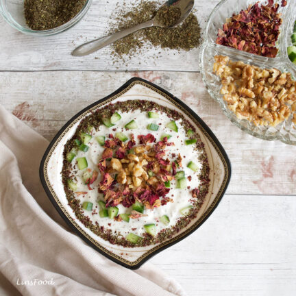 mast o khiar, persian yoghurt and cucumber dip in diamond shaped bowl, garnished with walnuts and dried rose petals
