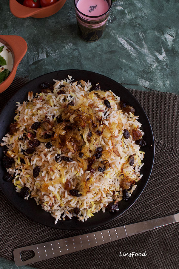 persian rice with noodles topped with caramelised onions and raisins on a black plate