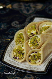pancake filled with cream and pistachios pile on a small rectangular plate